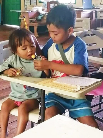 Agusan bóc kẹo cho em ăn để dỗ em ngồi ngoan. Ảnh: Herald Hope Tero-Mangle Apole