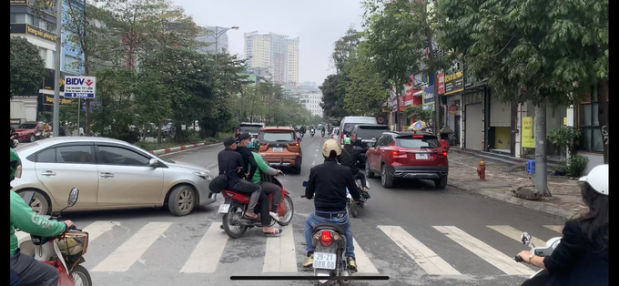 Bất chấp nguy hiểm, tài xế mặc áo Grab chở hai hành khách trong tình trạng không đội mũ bảo hiểm.