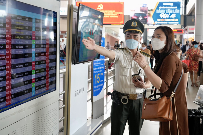 Nhân viên An ninh hàng không hướng dẫn khách cách xem thông tin chuyến bay trên màn hình thông báo bay (FIDS)